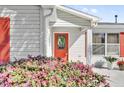 Inviting close-up of the front door with red trim, a decorative wreath, and blooming bushes at 9511 Se 168Th Elderberry Pl, The Villages, FL 32162