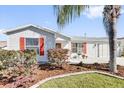 Single-story home featuring well-manicured lawn, vibrant foliage, front-facing garage and a welcoming red front door at 9511 Se 168Th Elderberry Pl, The Villages, FL 32162