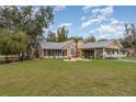 Charming single-story home with a well-manicured lawn, screened porch, and attached carport at 11415 Palmetto Dr, Tavares, FL 32778