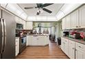 Well-lit kitchen with stainless steel appliances, white cabinets, and wood-look flooring at 132 E Belt Ave, Bushnell, FL 33513