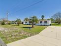 Angle view of a single-story home showcasing the palm trees and driveway at 13877 County Road 109F, Lady Lake, FL 32159