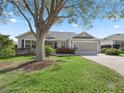 Inviting single-story home with a manicured lawn, mature trees, and a convenient two-car garage at 17635 Se 82Nd Annadale Ter, The Villages, FL 32162