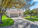 Inviting single-story home showcasing a well-maintained lawn, beautiful landscaping, and an attached two-car garage at 2039 Palo Alto Ave, The Villages, FL 32159