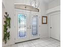 Elegant foyer with decorative glass double doors, white tile flooring, and a stylish light fixture at 2039 Palo Alto Ave, The Villages, FL 32159