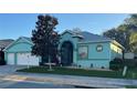 Charming single-story home with well-manicured lawn, two car garage and appealing turquoise exterior at 25517 Laurel Valley Rd, Leesburg, FL 34748