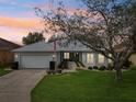 Charming single story home with a well-manicured lawn, an American flag, and an attached two-car garage at 26821 Augusta Springs Cir, Leesburg, FL 34748