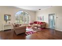 Bright living room with hardwood floors, comfortable seating and a large arched window at 288 Bent Oak Ct, Leesburg, FL 34748