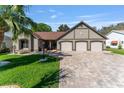 Charming single-Gathering home with a paver driveway, three-car garage and manicured front lawn with palm tree at 314 Chula Vista Ave, Lady Lake, FL 32159