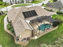 Aerial view showcasing a screened-in pool, solar panels, and lush green landscaping at 5029 Greenbriar Trl, Mount Dora, FL 32757