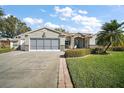 Inviting single-story home featuring a well-manicured lawn and a two-car garage with an arched entry at 509 Grand Vista Trl, Leesburg, FL 34748