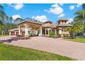 Beautiful view of the estate home featuring a covered portico, brick driveway, and well manicured landscaping at 6801 Silver Charm Ct, Leesburg, FL 34748