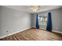 Comfortable bedroom featuring hardwood floors, a ceiling fan, and a bright window with blue curtains at 723 Palma Dr, Lady Lake, FL 32159