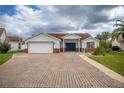 Charming single-story home featuring a brick-paved driveway, well-maintained landscaping, and an attached two-car garage at 723 Palma Dr, Lady Lake, FL 32159