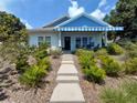 Beautiful home with a blue awning, complemented by lush landscaping and a welcoming walkway at 1013 Lake Elsie Dr, Tavares, FL 32778