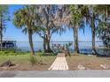 Brick path leads to waterfront dock with two Adirondack chairs and palm trees framing the view at 11215 Dead River Rd, Tavares, FL 32778
