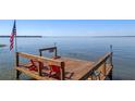 Lake view from a private wooden dock with red Adirondack chairs and American flag at 11215 Dead River Rd, Tavares, FL 32778