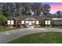Well-maintained brick home with lush landscaping and large circular driveway at 11215 Dead River Rd, Tavares, FL 32778