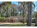 Charming brick home surrounded by mature trees and landscaping with circular driveway at 11215 Dead River Rd, Tavares, FL 32778