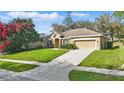Well-maintained single-Gathering home featuring lush green lawn and a long driveway on a sunny day at 13753 Via Roma Cir, Clermont, FL 34711