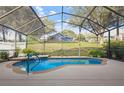 Relaxing screened-in pool featuring a waterfall, blue handrail, and a serene backyard view at 13753 Via Roma Cir, Clermont, FL 34711