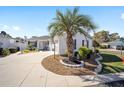 Attractive single-story home with a circular driveway, white exterior, and verdant landscaping featuring a tall palm tree at 16800 Se 80Th Bathurst Ct, The Villages, FL 32162