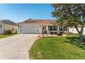 Charming single-story home with a two-car garage and a cozy outdoor seating area on the front yard at 17416 Se 71St Currituck Ter, The Villages, FL 32162