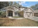 Two-story home featuring a well-manicured lawn, mature landscaping, and a two-car garage at 17421 Woodfair Dr, Clermont, FL 34711