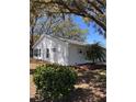 Side exterior of home with a landscaped yard, lush green bushes, and a young palm tree at 25527 Oak Aly, Leesburg, FL 34748