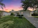 Charming single-story home features a well-manicured lawn and inviting entrance at sunset at 3337 Ashbrook Pl, The Villages, FL 32162