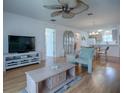 Cozy living area with sleek TV, hardwood floors, and a ceiling fan with seamless flow into the kitchen at 3337 Ashbrook Pl, The Villages, FL 32162