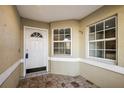 Inviting front porch area with stone tile flooring and a white front door and large windows at 33624 Dolores Ct, Leesburg, FL 34788