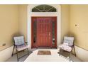 Welcoming front porch featuring a red front door with glass sidelights and comfortable seating at 3373 Melbourne Ln, The Villages, FL 32163