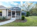 View of the screened lanai and backyard featuring green grass, trees, and tropical plants at 36845 Taylor Mill Rd, Fruitland Park, FL 34731