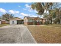 Inviting single-story brick home with detached garage, mature trees, and a spacious front lawn at 448 E Waldo St, Groveland, FL 34736