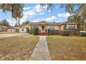 Charming single-story brick home with a walkway leading to a welcoming red porch and mature landscaping at 448 E Waldo St, Groveland, FL 34736