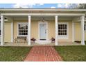 Inviting front porch featuring a brick walkway, bench seating, columns and decorative flowerpots at 502 Lake Gracie Dr, Eustis, FL 32726