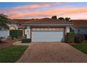 Beautiful home with a tile roof, brick driveway, and meticulous landscaping at dusk at 5056 Harbour Dr, Oxford, FL 34484