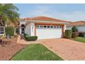Charming single-story home with a tile roof, brick driveway, and meticulously maintained landscaping at 5056 Harbour Dr, Oxford, FL 34484