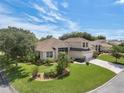 Charming home with a well-manicured lawn, mature trees, and a paver driveway under a blue sky at 6122 Sailboat Ave, Tavares, FL 32778