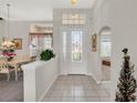 Inviting foyer with tile flooring, half-wall divider, and decorative glass front door with transom window at 6122 Sailboat Ave, Tavares, FL 32778