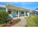 Inviting front porch with white columns, complemented by a landscaped garden bed, creating a welcoming entry at 1033 Scotch Pine Ct, Leesburg, FL 34788