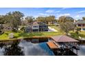 Backyard view of a luxurious home with a private dock and boat lift on a serene lake at 11007 Lake Katherine Cir, Clermont, FL 34711