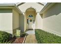Inviting front entrance with an arched doorway, a decorative wreath, and a well-maintained walkway and landscape at 11684 Sw 72Nd Cir, Ocala, FL 34476