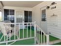 Inviting front porch with comfortable seating and a view of the well-maintained landscaping and charming white exterior at 1340 Elkhart Cir, Tavares, FL 32778