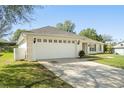 A two-car garage with carriage doors is complemented by a well-maintained driveway and manicured front lawn at 1792 Presidio Dr, Clermont, FL 34711