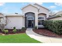 Inviting front entrance with a curved walkway and lush landscaping at 20755 Queen Alexandra Dr, Leesburg, FL 34748