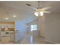 Open-concept living space with high ceilings, a fan, and modern flooring flows to the kitchen at 2082 Harston Trl, The Villages, FL 32162