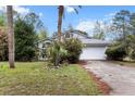 A single-Gathering home shows its front exterior with a two-car garage, mature trees and front yard at 21311 Sw Marine Blvd, Dunnellon, FL 34431