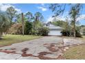 A house with mature landscaping shows its front exterior with a two-car garage at 21311 Sw Marine Blvd, Dunnellon, FL 34431