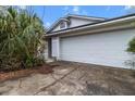 Attached two-car garage with a white door; a mature palm and established shrubbery line the front at 21311 Sw Marine Blvd, Dunnellon, FL 34431